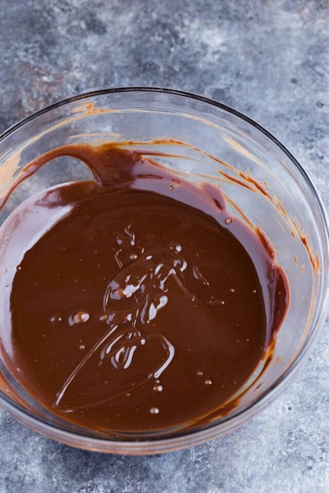 Melted chocolate ganache in a glass bowl.