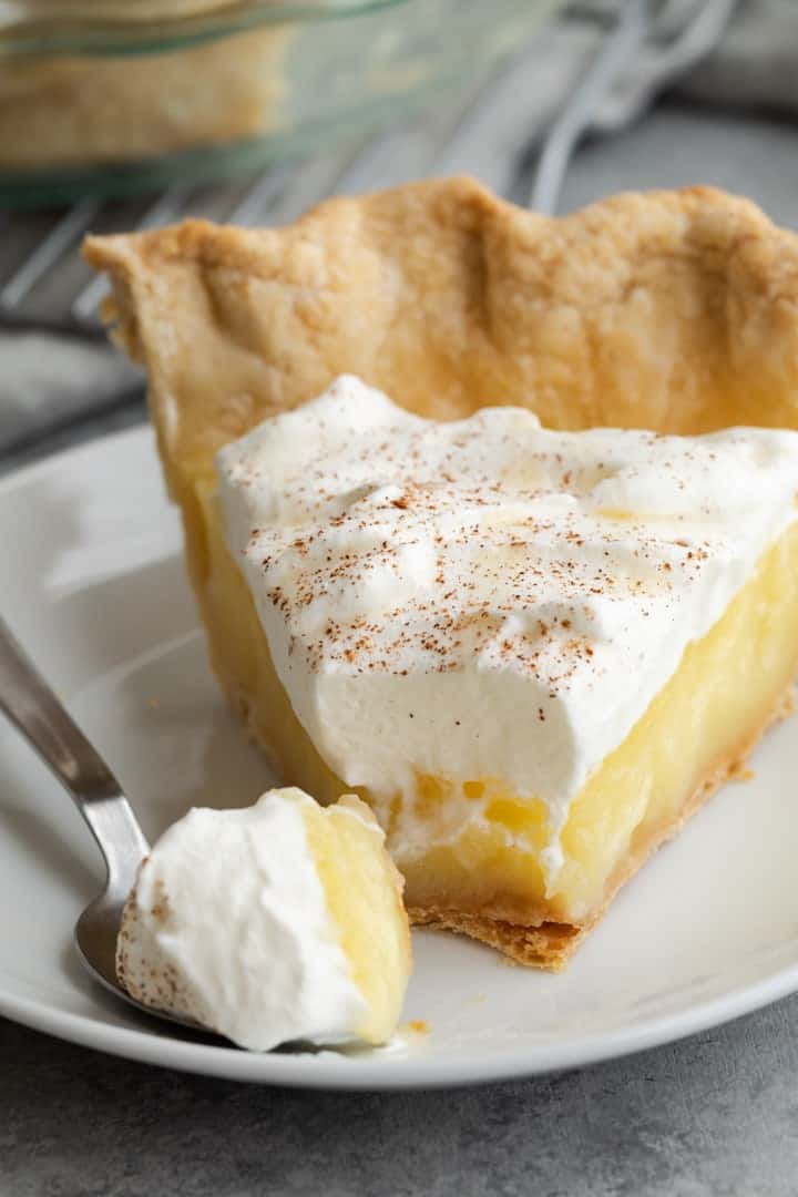 slice of vinegar pie on a white plate with a fork taking a bite out