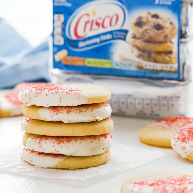 White chocolate peppermint cookies stacked on a piece of white parchment paper with a Crisco package behind it.