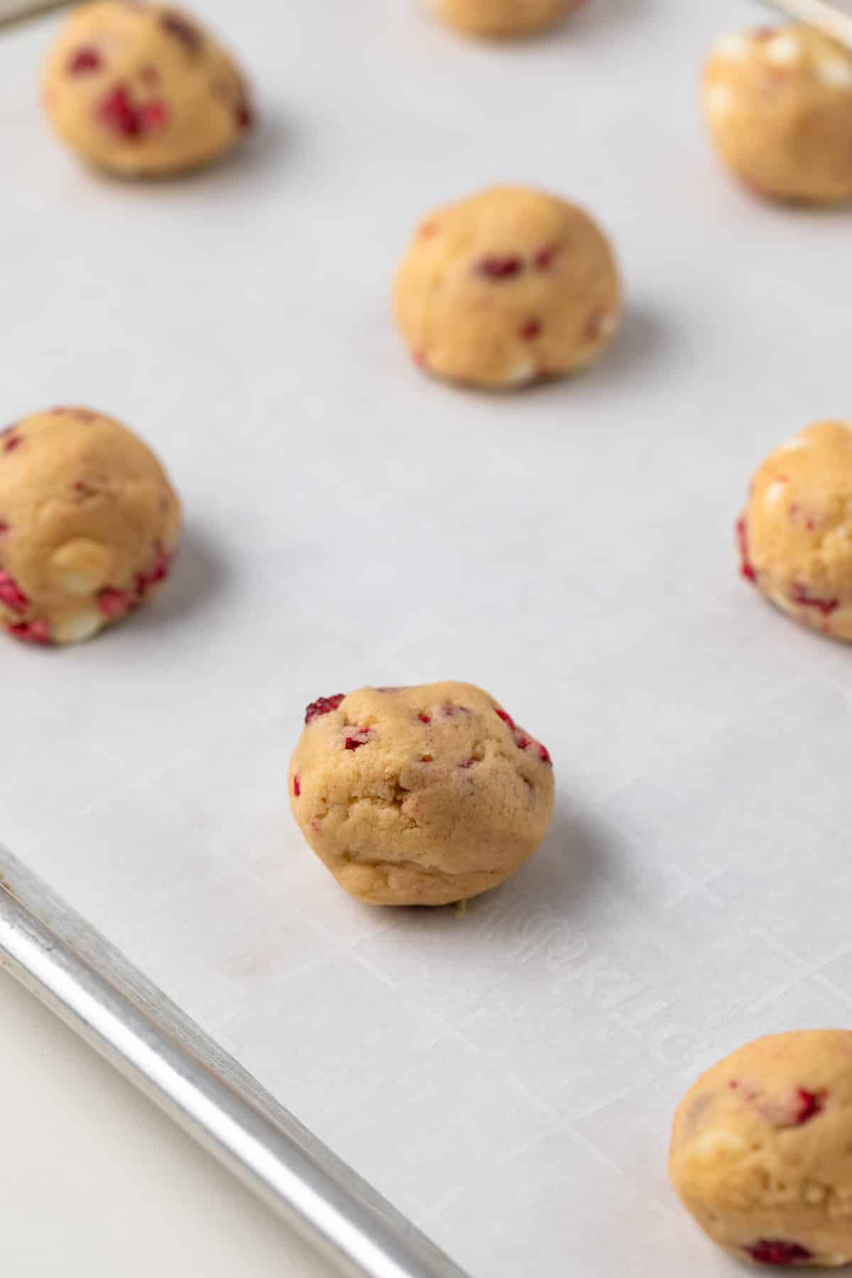 Unbaked cookie dough balls on sheet pan.