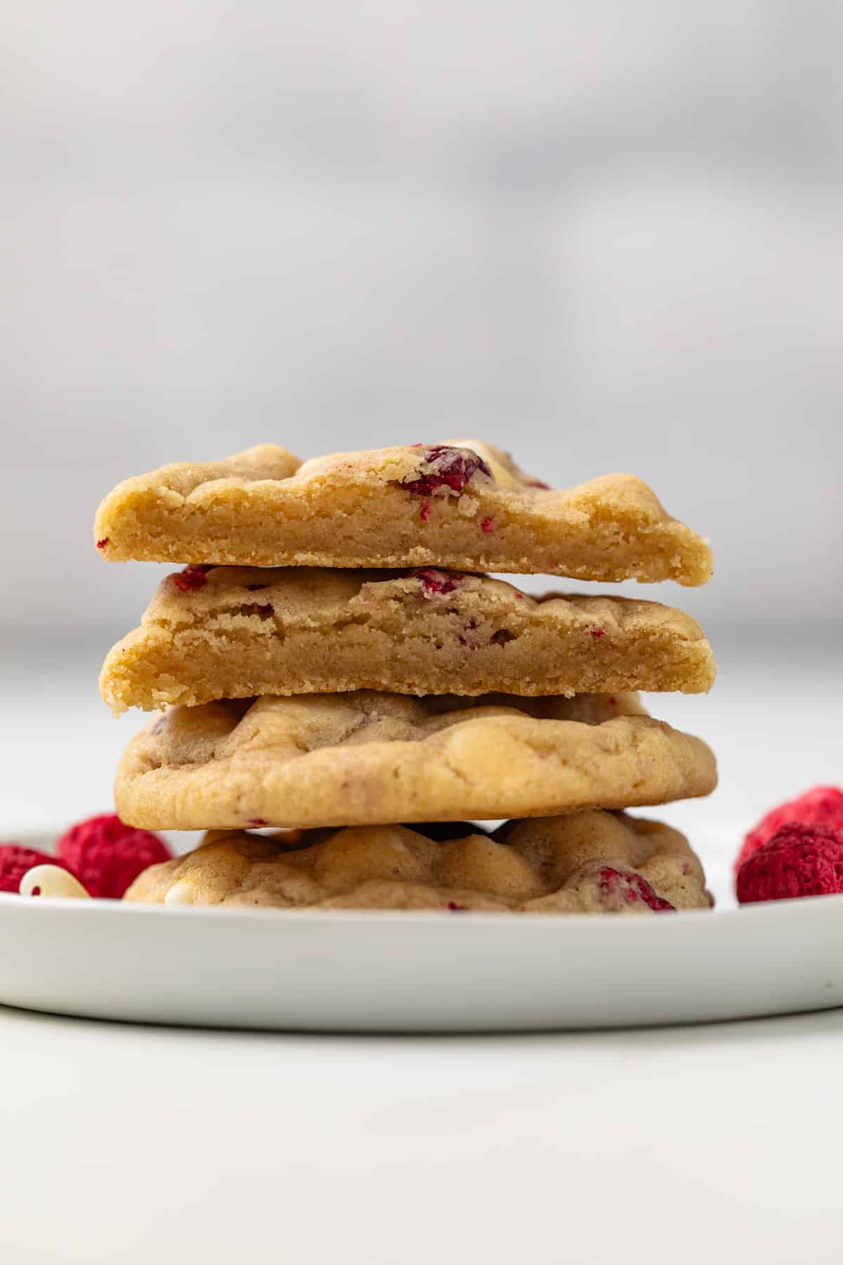 Stack of white chocolate raspberry cookies with on cut in half.