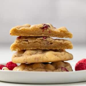 Stack of white chocolate raspberry cookies with on cut in half.