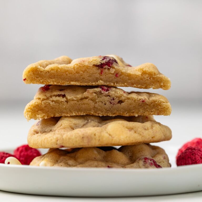 Stack of white chocolate raspberry cookies with on cut in half.