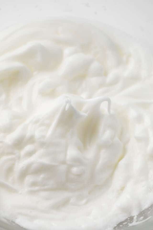Whipped egg whites in glass bowl.